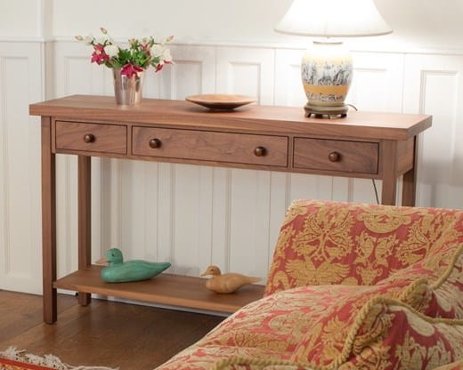 Walnut console table with three drawers, lower shelf and a table lamp