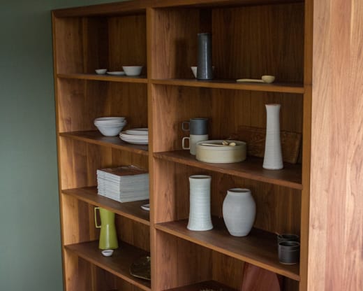 Walnut bookcase shelving displaying ceramics and pottery