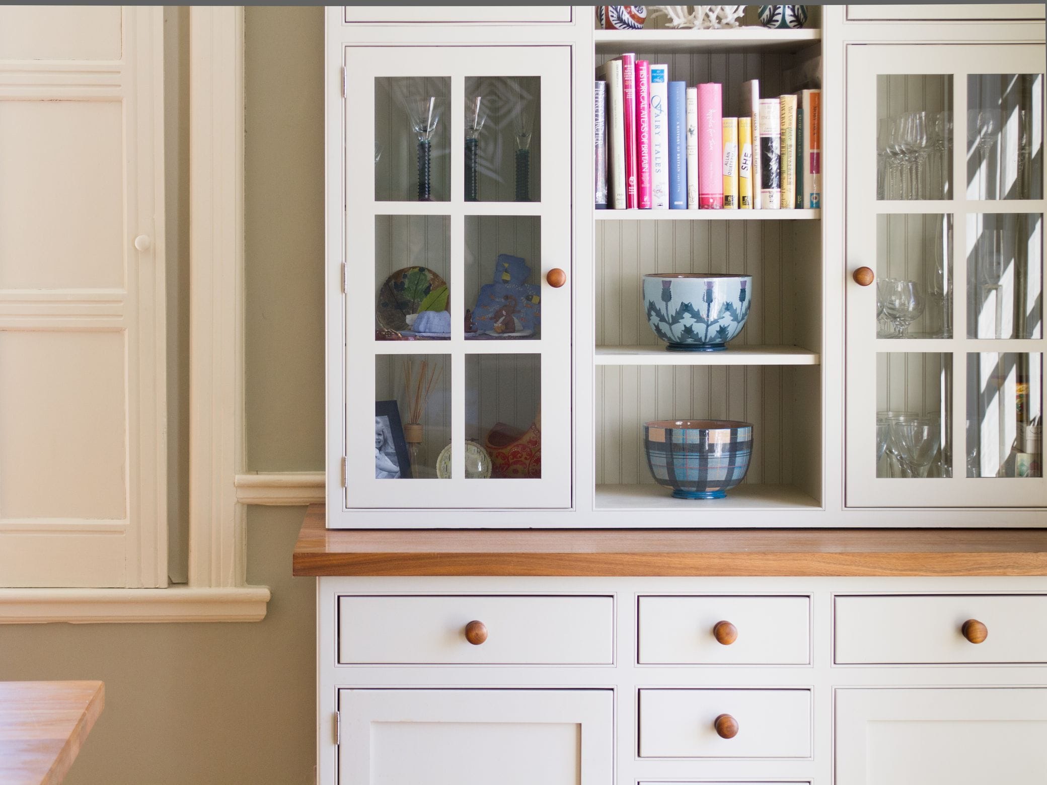 Cream painted kitchen dresser with glazed doors, open shelves and an oak counter