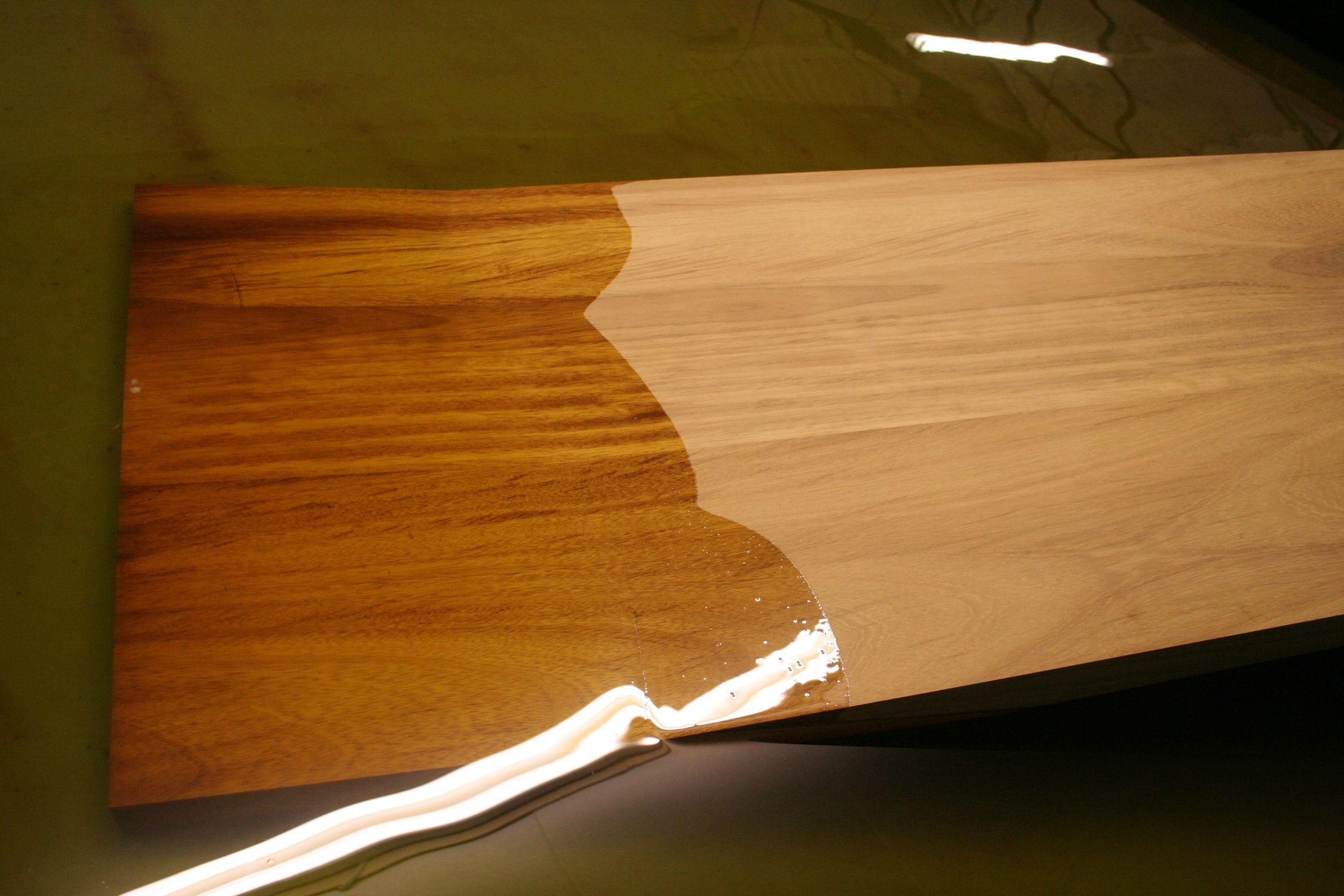 Half-oiled iroko board showing the contrast between raw and oiled timber