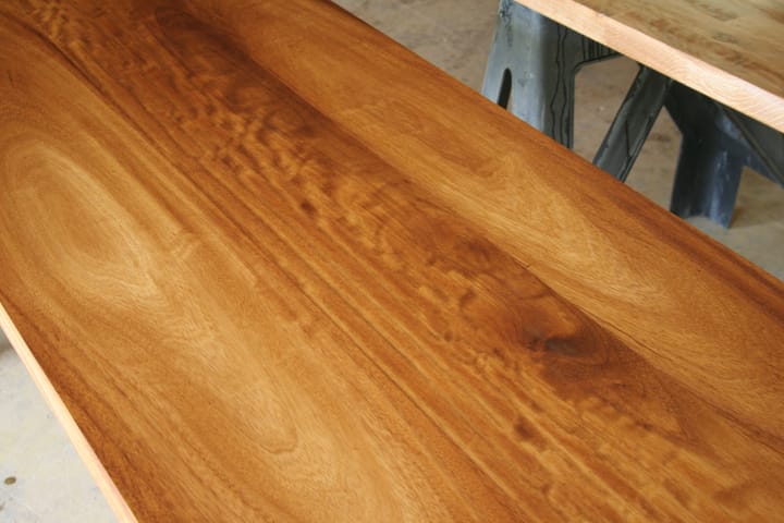 Long oiled iroko worktop on trestles showing rippled golden grain