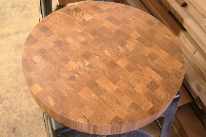 Round oak end grain chopping block on a stand in the workshop