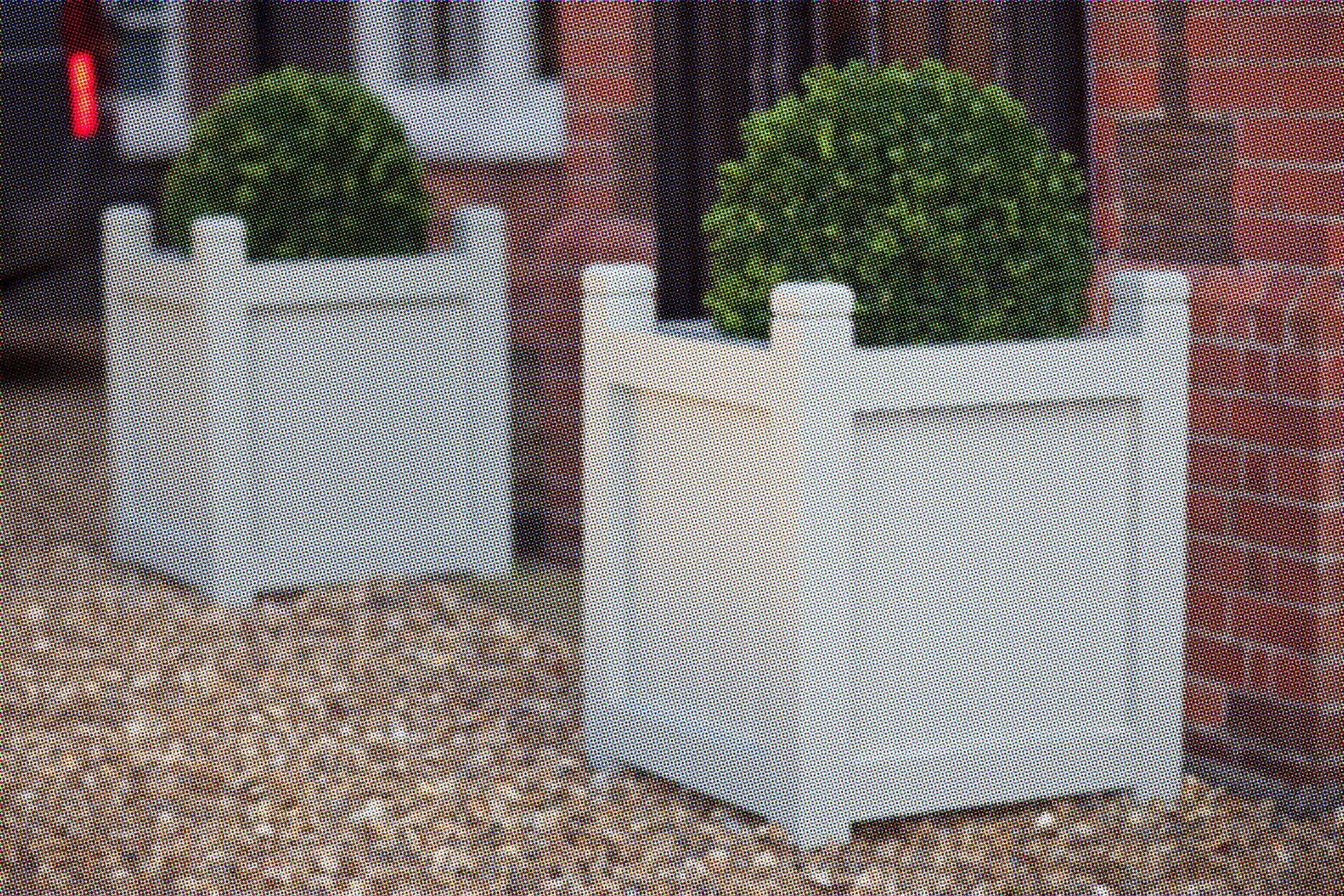Pair of grey painted wooden garden planters with clipped box balls on a gravel path