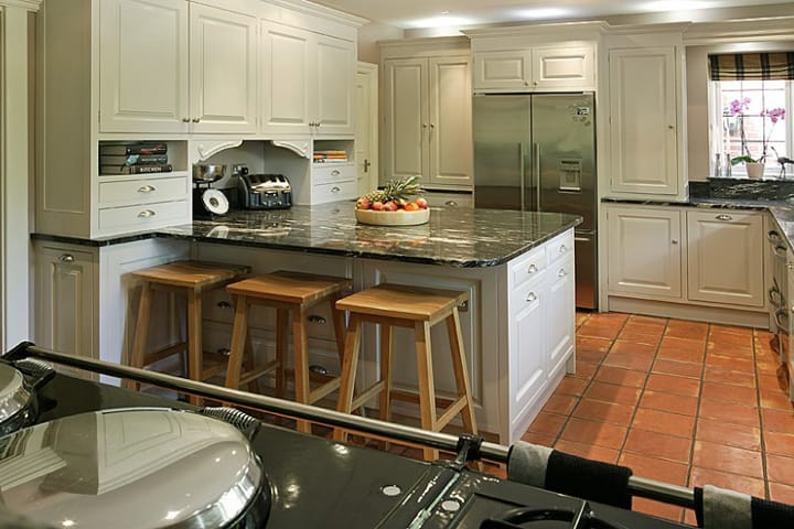 Cream painted kitchen with granite-topped island and three oak bar stools