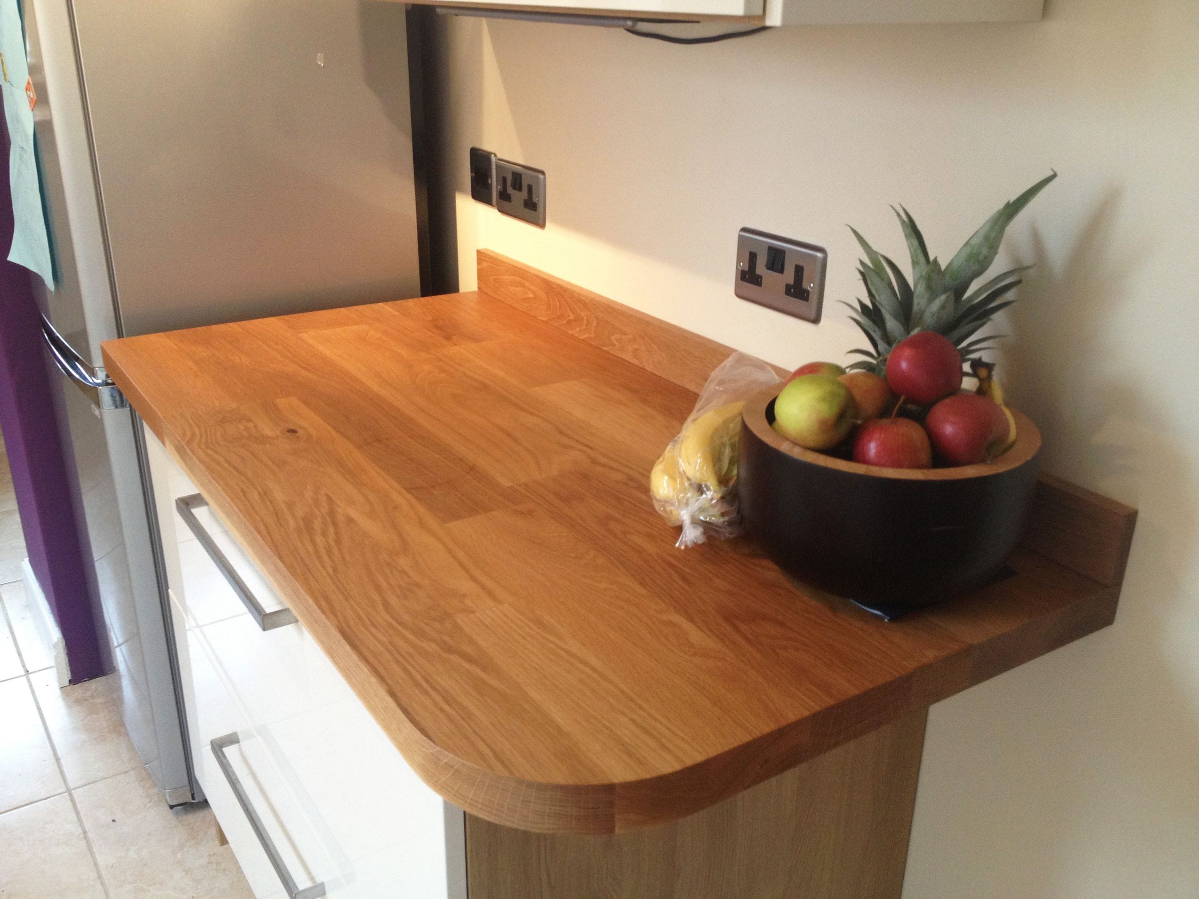 Oak worktop with rounded corner and fruit bowl beside a fridge freezer