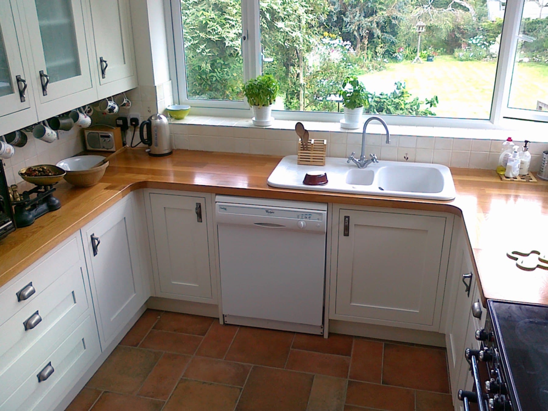 Cream Shaker kitchen with oak worktops and white sink overlooking a garden