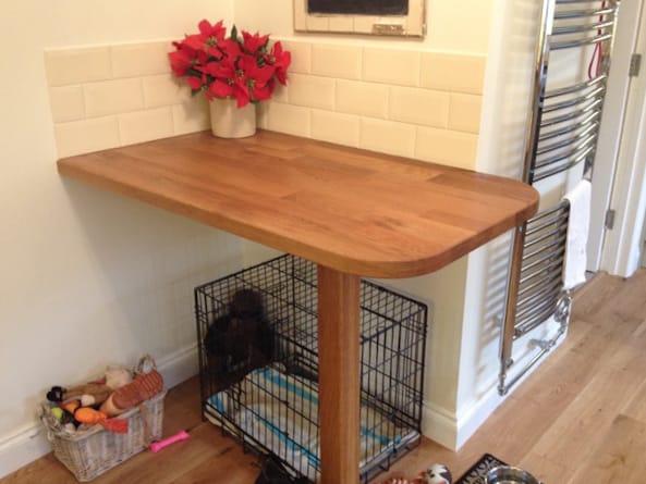 Wall-mounted oak breakfast bar fitted above a dog crate, poinsettia on top