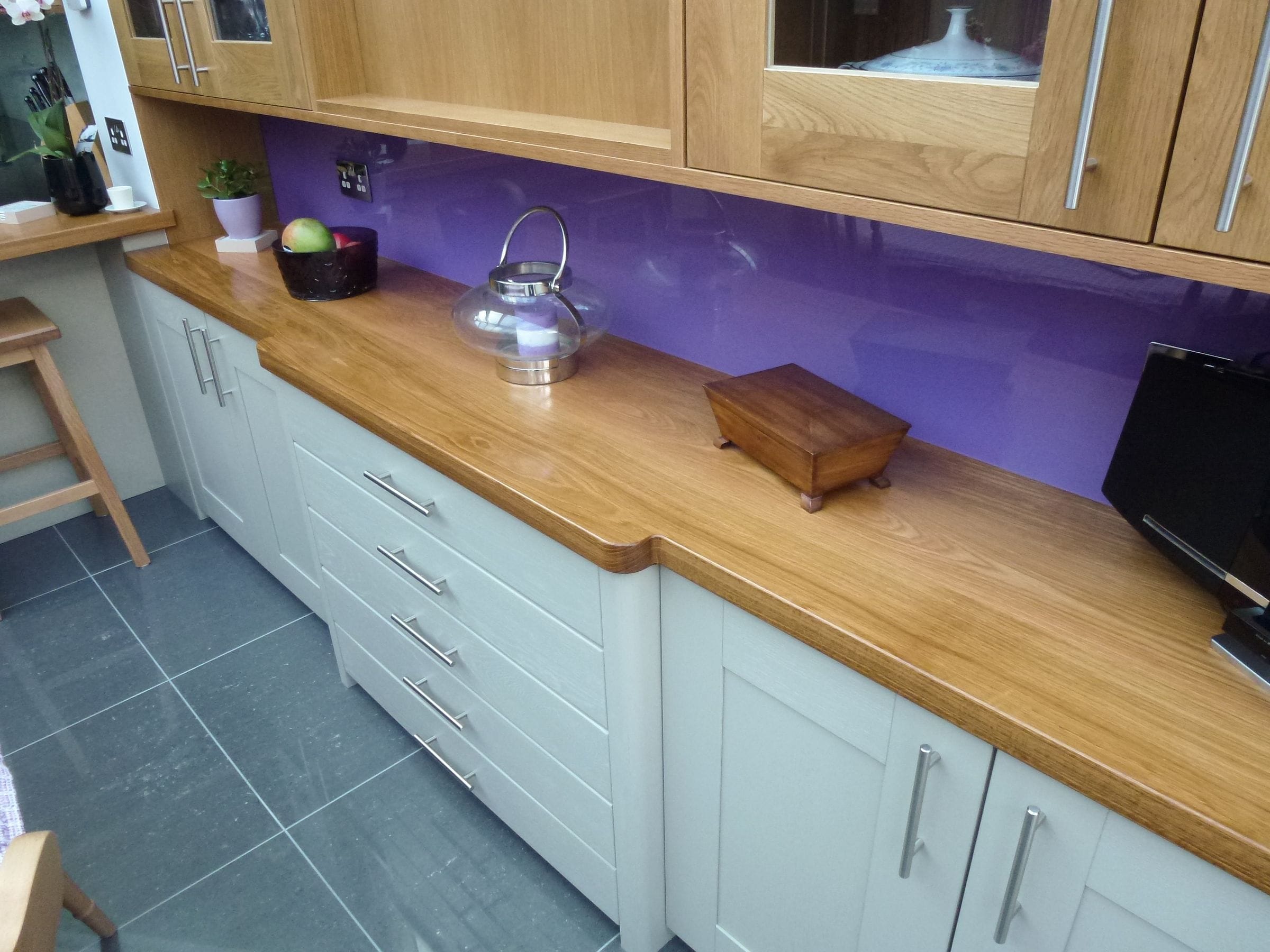 Oak super stave worktop with purple glass splashback and oak wall cabinets