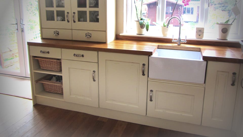Oak worktop with drainer grooves and Belfast sink on cream painted units