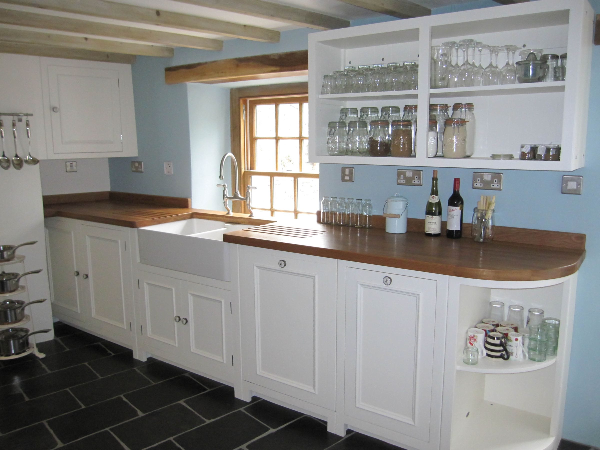 Cottage kitchen with oak worktops, white cabinets, Belfast sink and exposed ceiling beams
