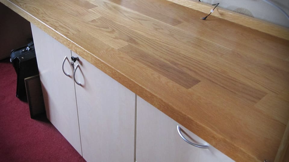Close view of an oiled oak worktop with staggered staves on pale cabinet doors