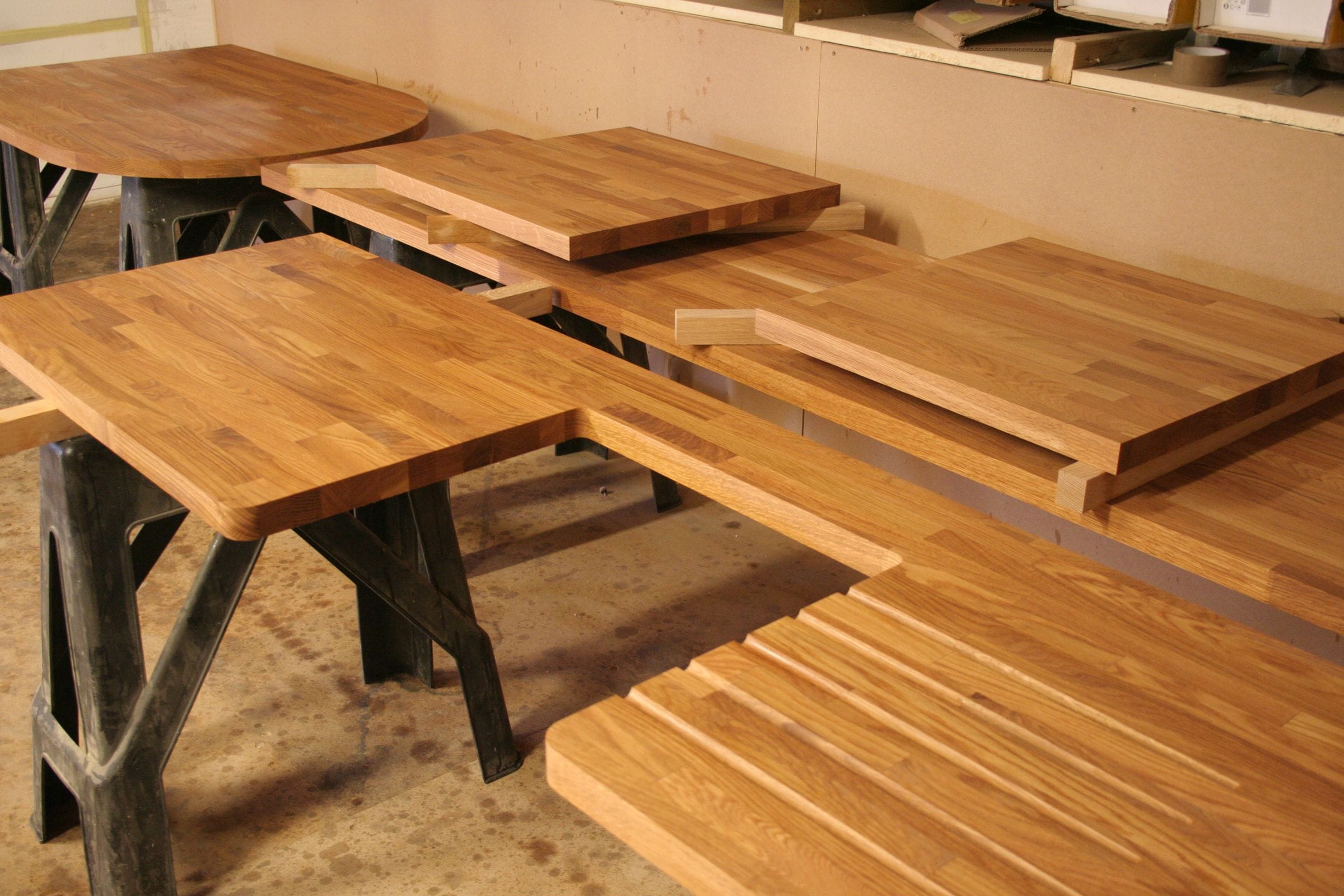 Freshly finished oak worktops resting on trestles in the workshop, one with a grooved drainer
