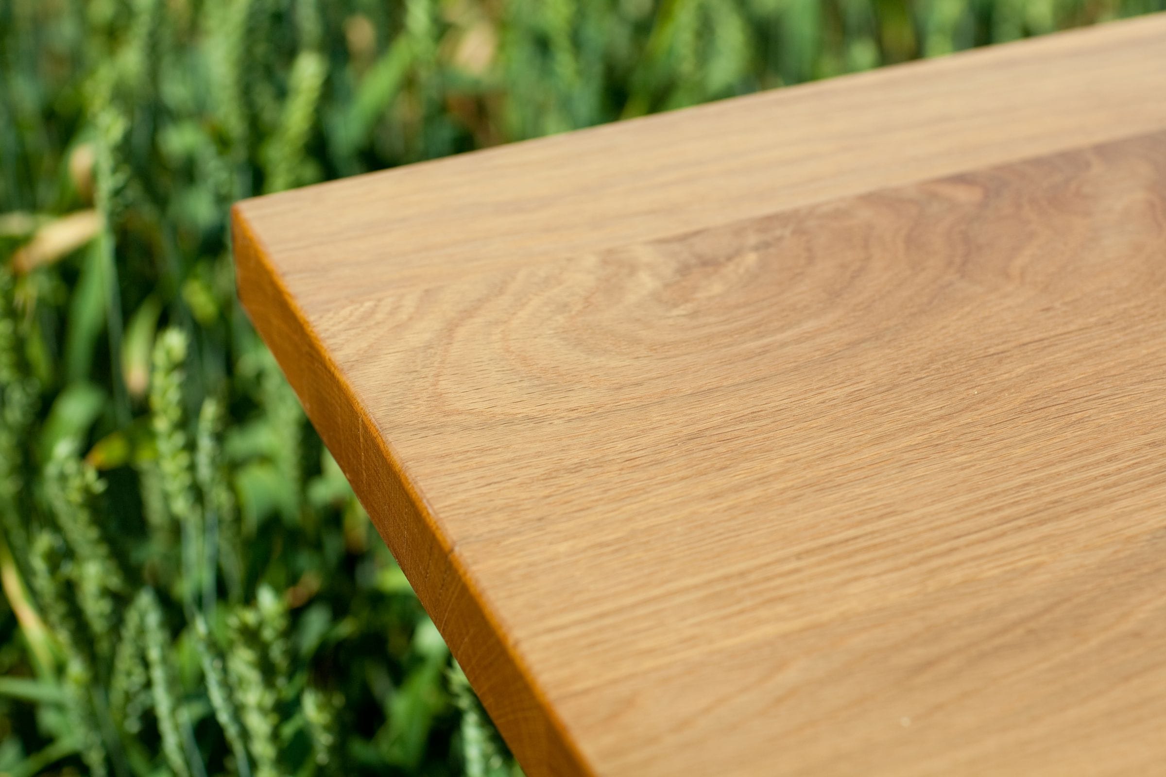Close-up of the corner of an oiled oak worktop photographed in a wheat field