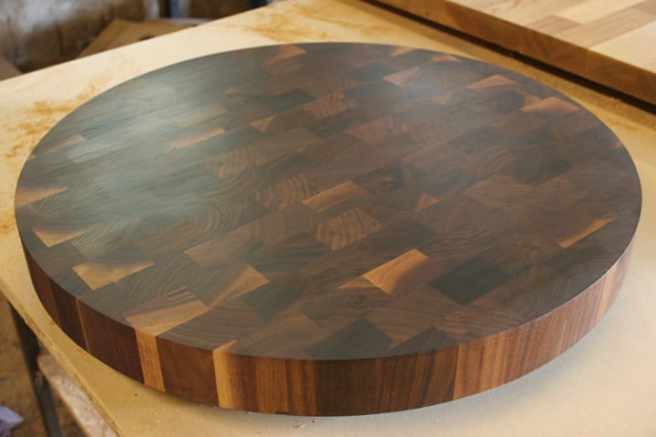Round walnut end grain chopping block on a workshop bench