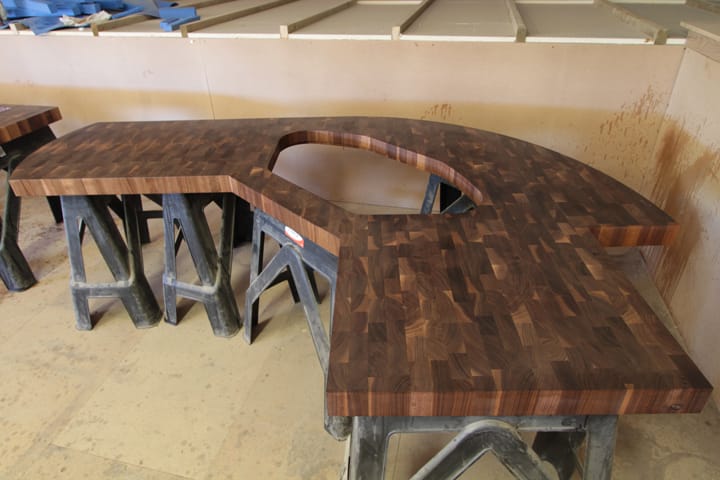 Curved walnut end grain worktop with hob cutout supported on trestles