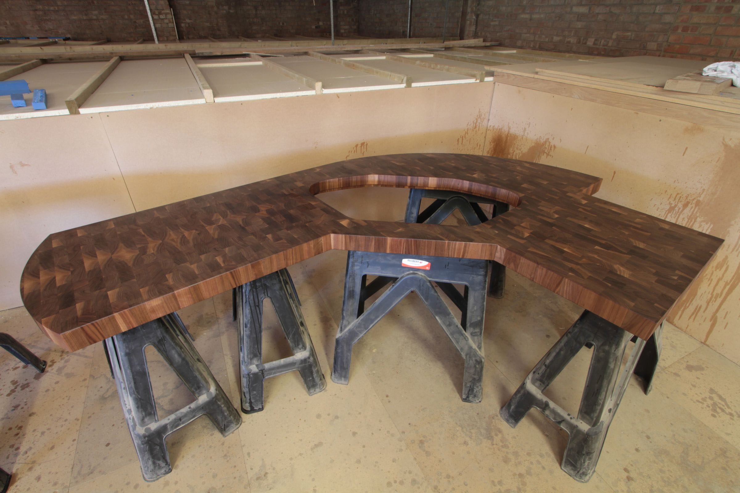 Large sweeping walnut end grain worktop on trestles in the workshop