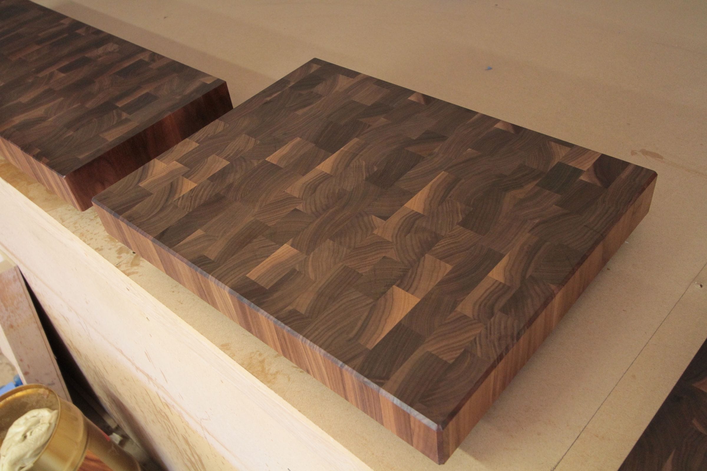 Thick walnut end grain chopping boards on a workshop bench