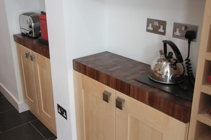 Walnut end grain worktops on pale maple cabinets with kettle and toaster