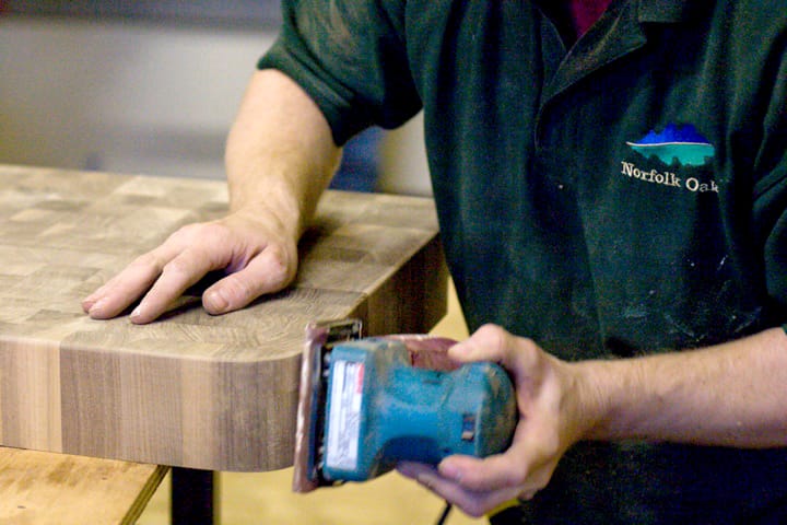Norfolk Oak craftsman hand-sanding a walnut end grain worktop