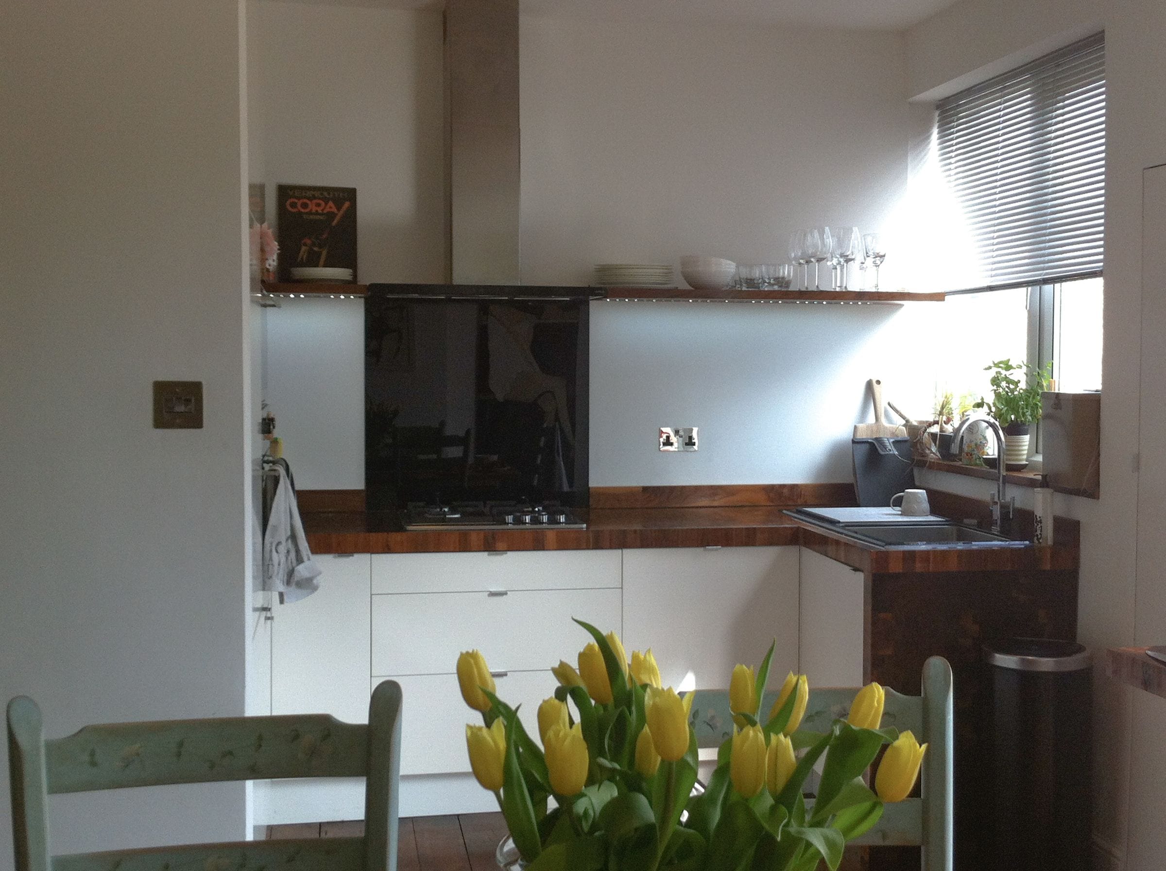 White kitchen with walnut end grain worktops, floating shelf and yellow tulips