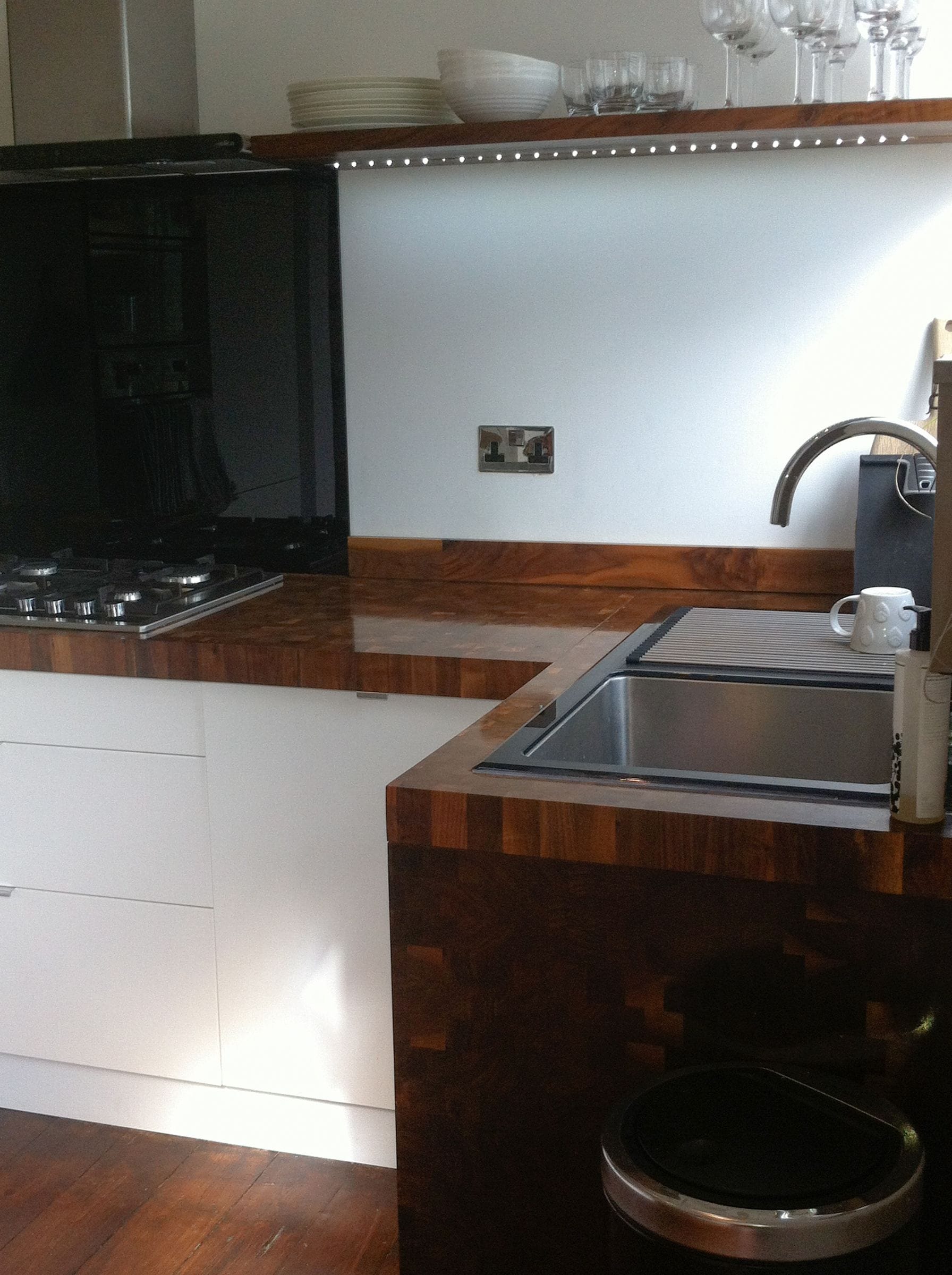 Walnut end grain worktops with deep waterfall end around an undermount sink in a white kitchen