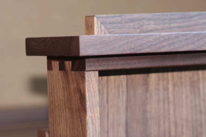 Close-up of finger-jointed corner detail on a walnut cabinet top