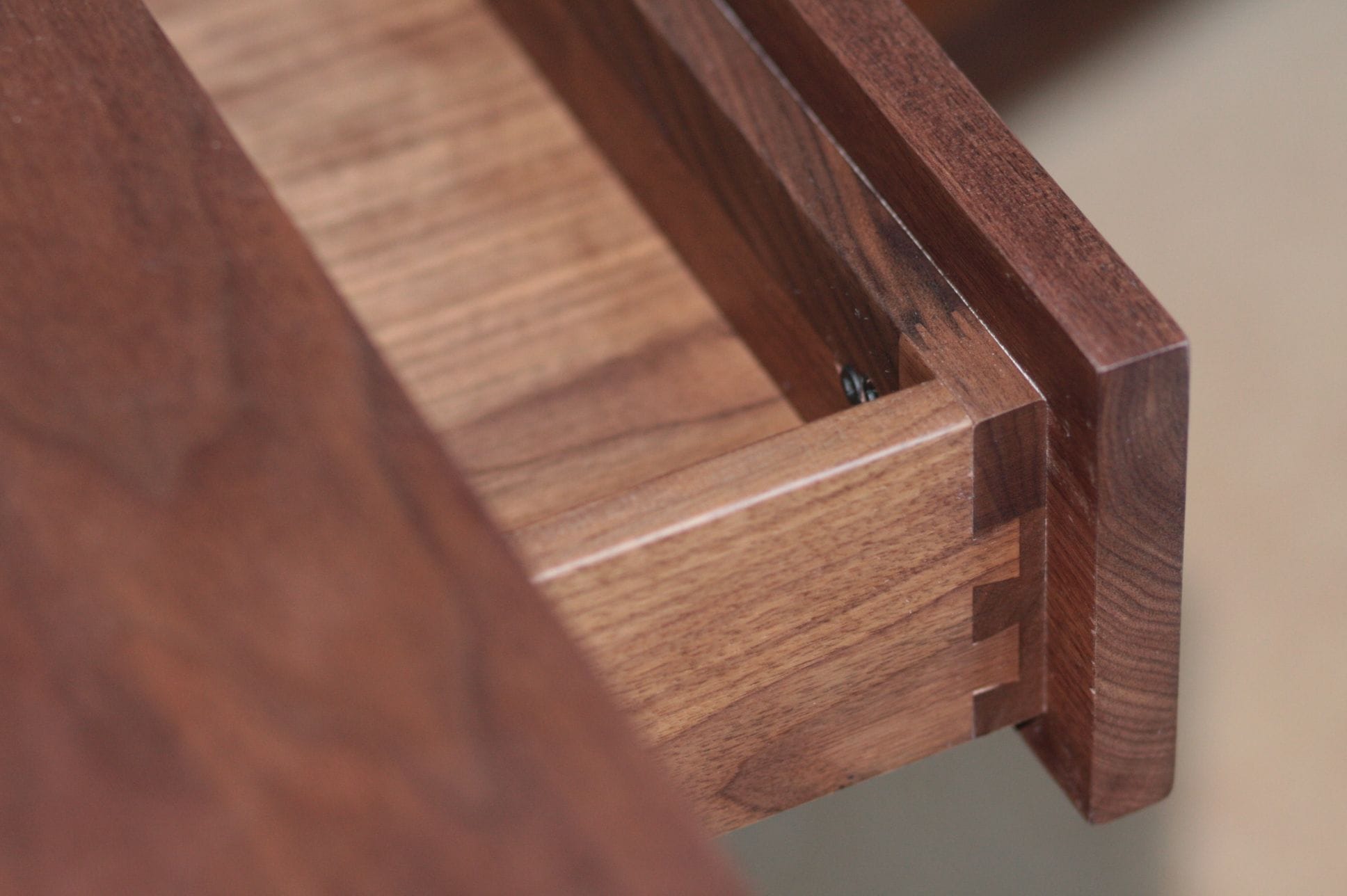 Dovetail-jointed corner of an open walnut drawer in close-up