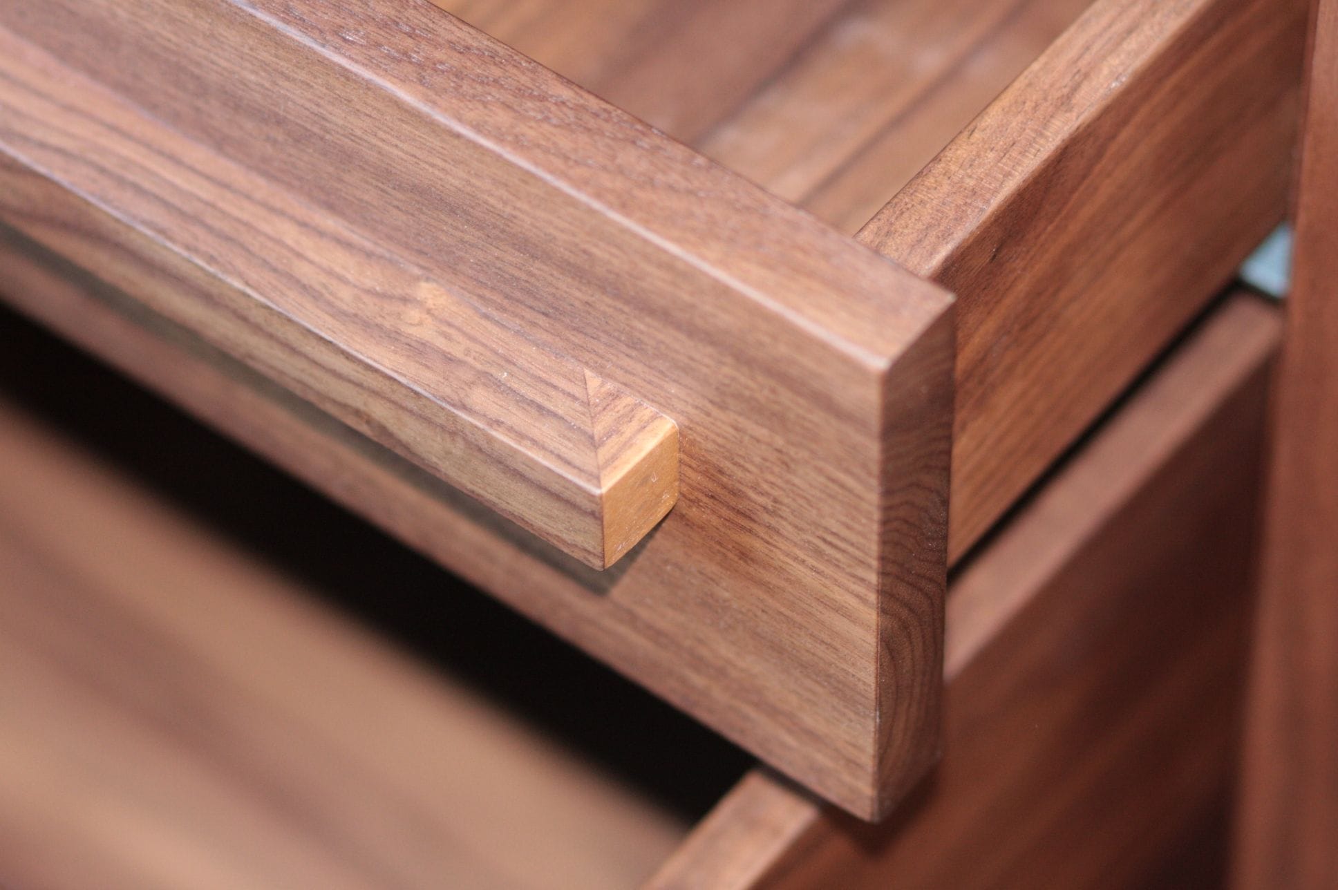 Detail of a solid walnut drawer front with slim wooden handle