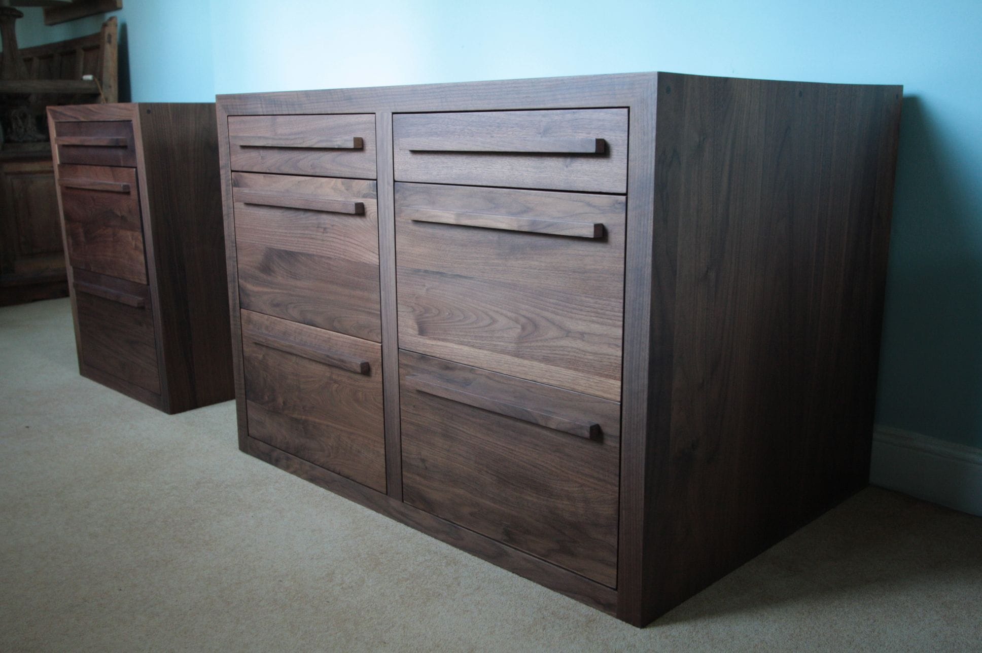Pair of handmade walnut drawer cabinets against a pale blue wall