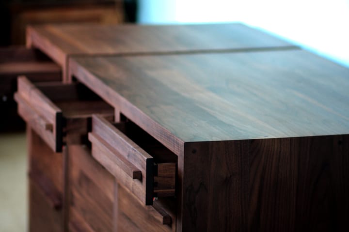 Walnut cabinets with open drawers, showing figured grain across the tops