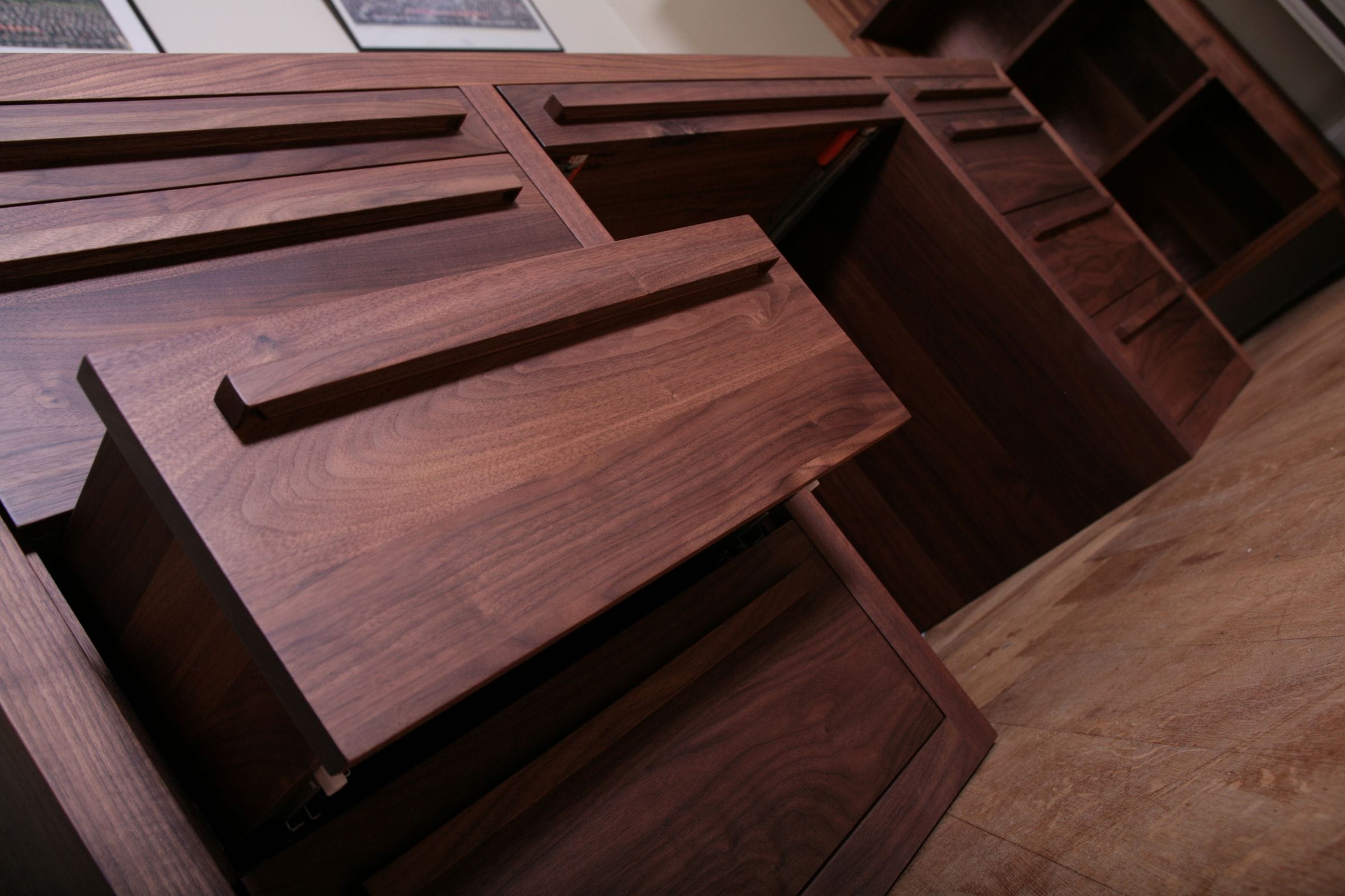 Angled view of a walnut home office unit with large drawers open