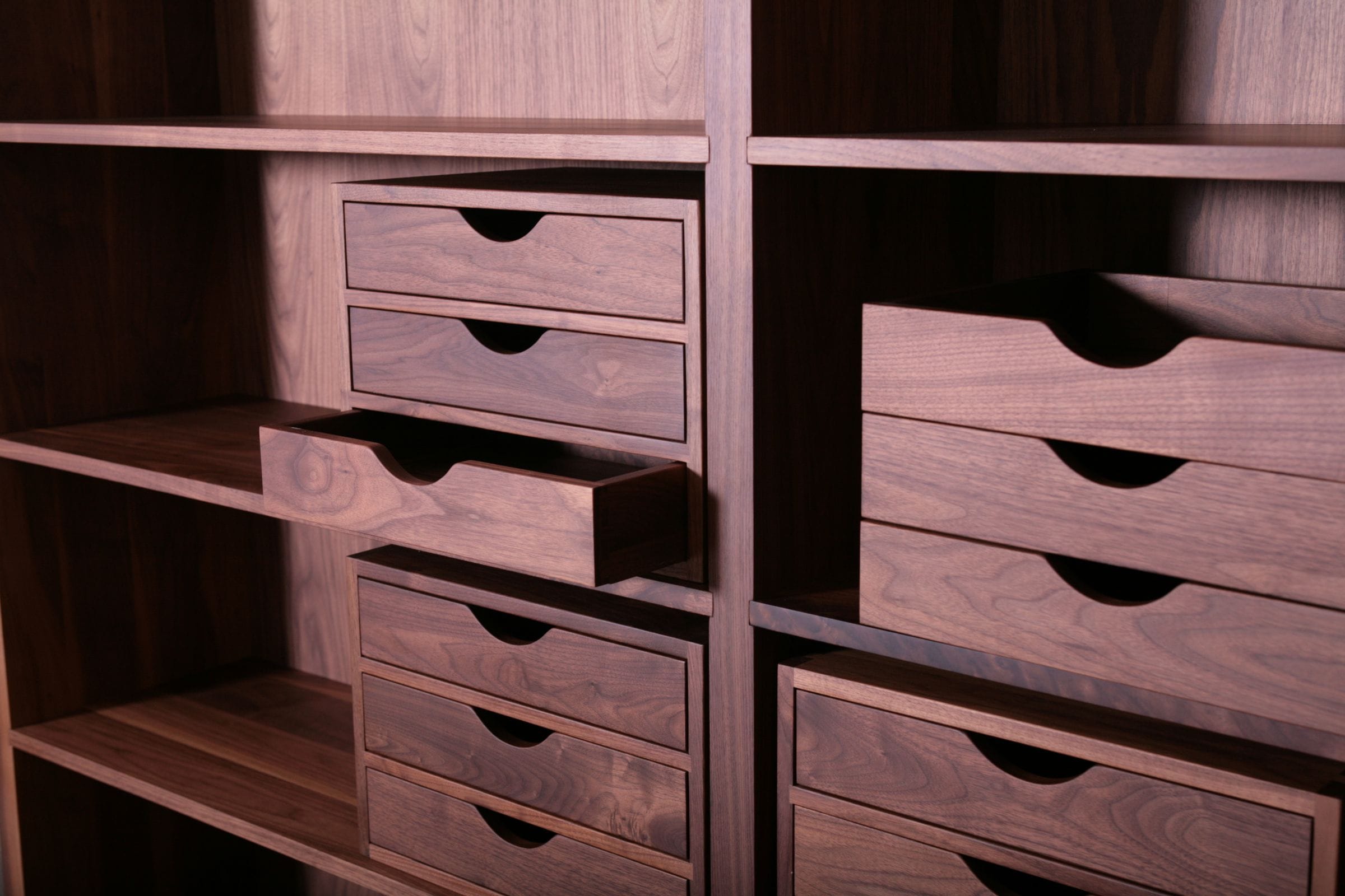Banks of small walnut drawers with scalloped pulls set within shelving
