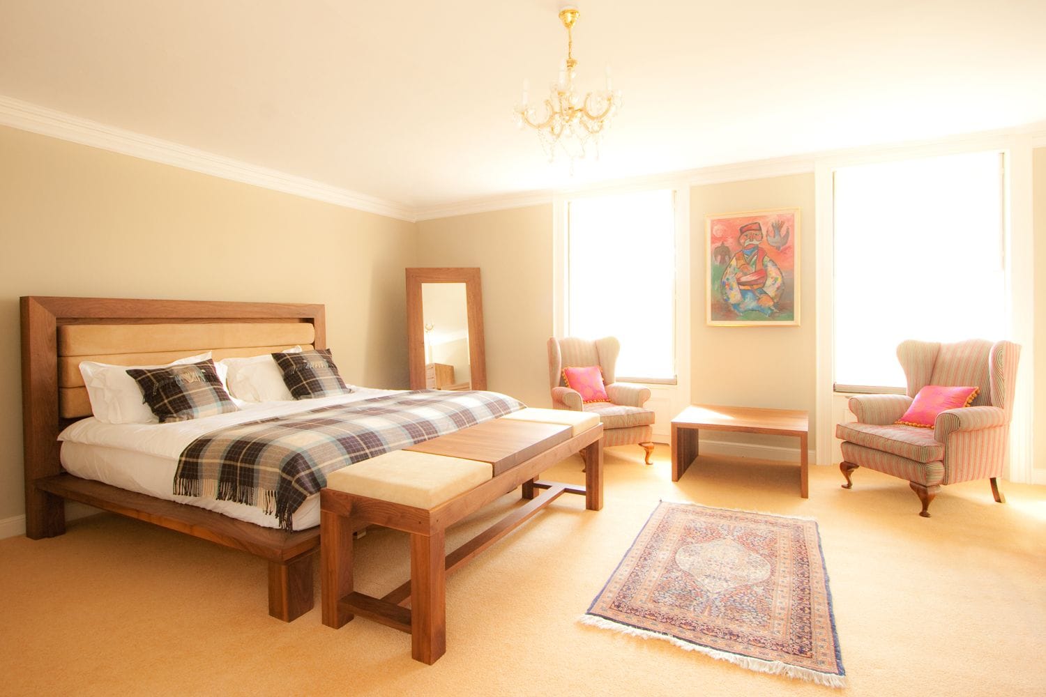 Bright bedroom furnished with a walnut bed, bench seat and leaning mirror