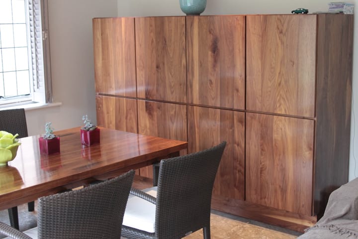 Large walnut cupboard with figured door panels behind a matching dining table