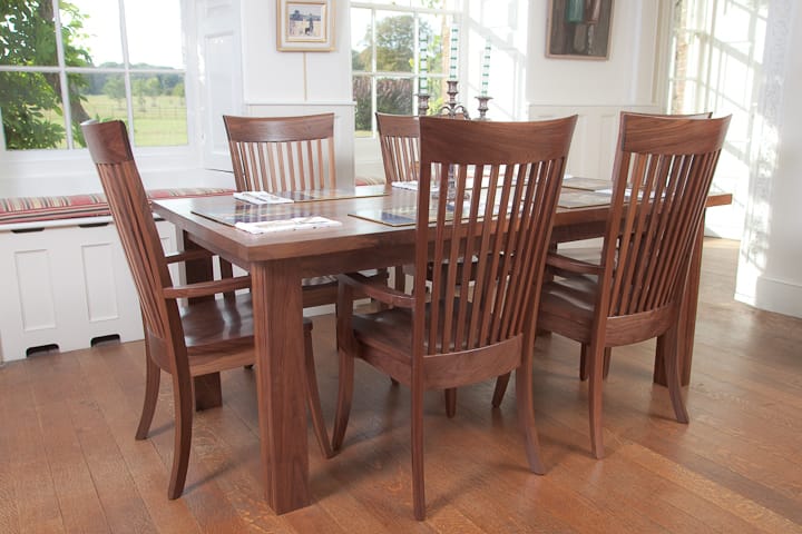 Walnut dining table and six high-backed slatted chairs on an oak floor