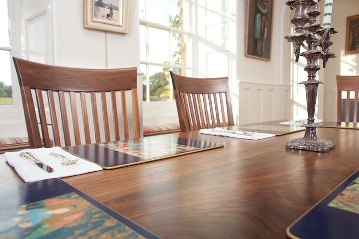 Walnut dining table set with placemats, napkins and an ornate silver candelabra