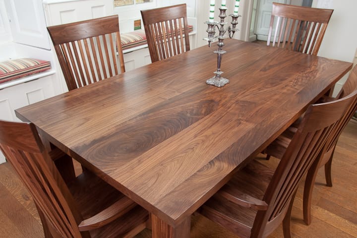 Walnut dining table with candelabra centrepiece and matching curved-back chairs