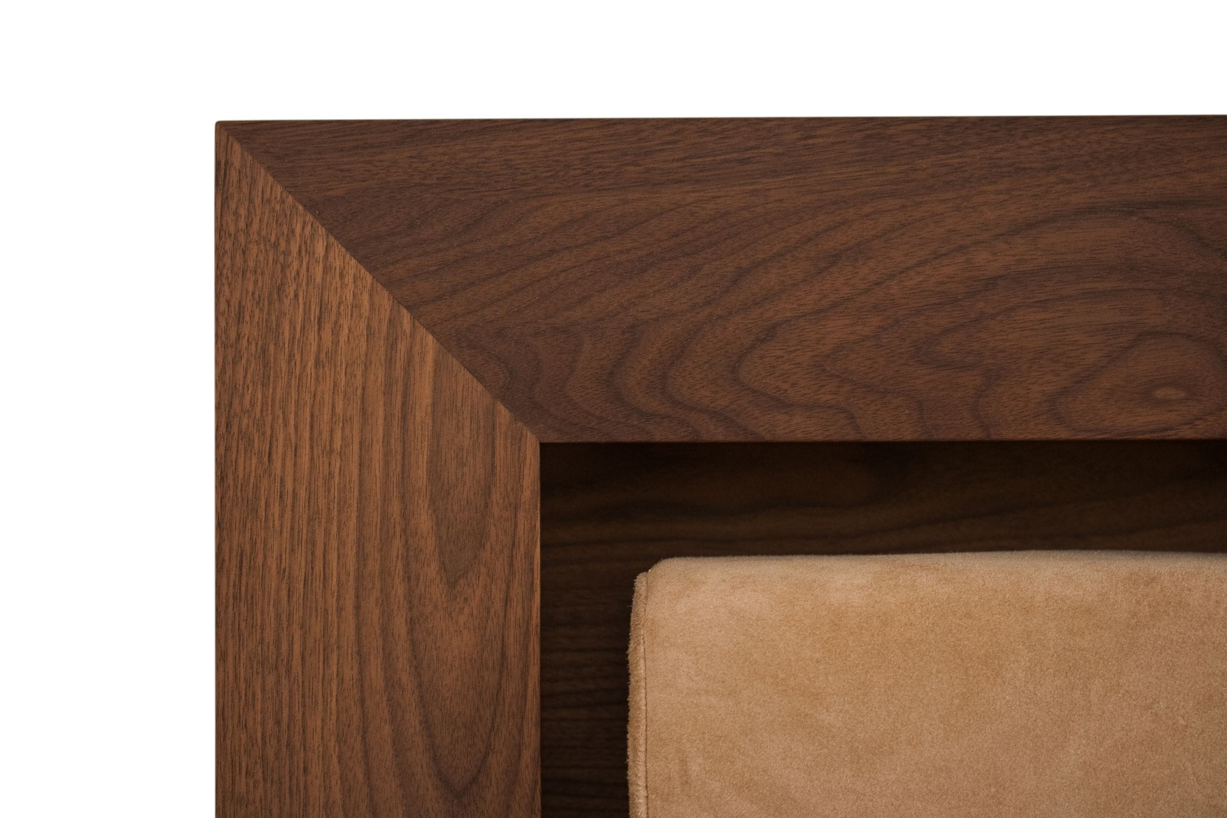 Mitred corner detail of a walnut headboard frame with suede upholstered panel