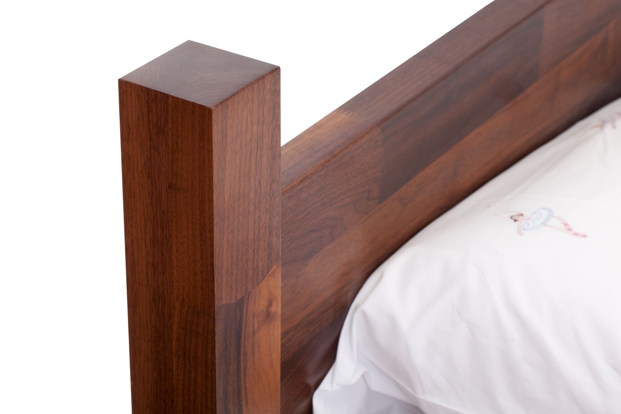 Close-up of a walnut bed's square corner post and headboard joinery