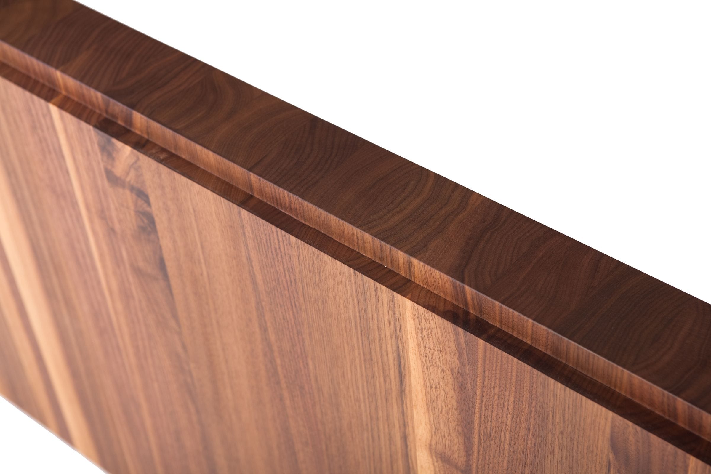 Angled close-up of a walnut headboard edge with chamfered top rail