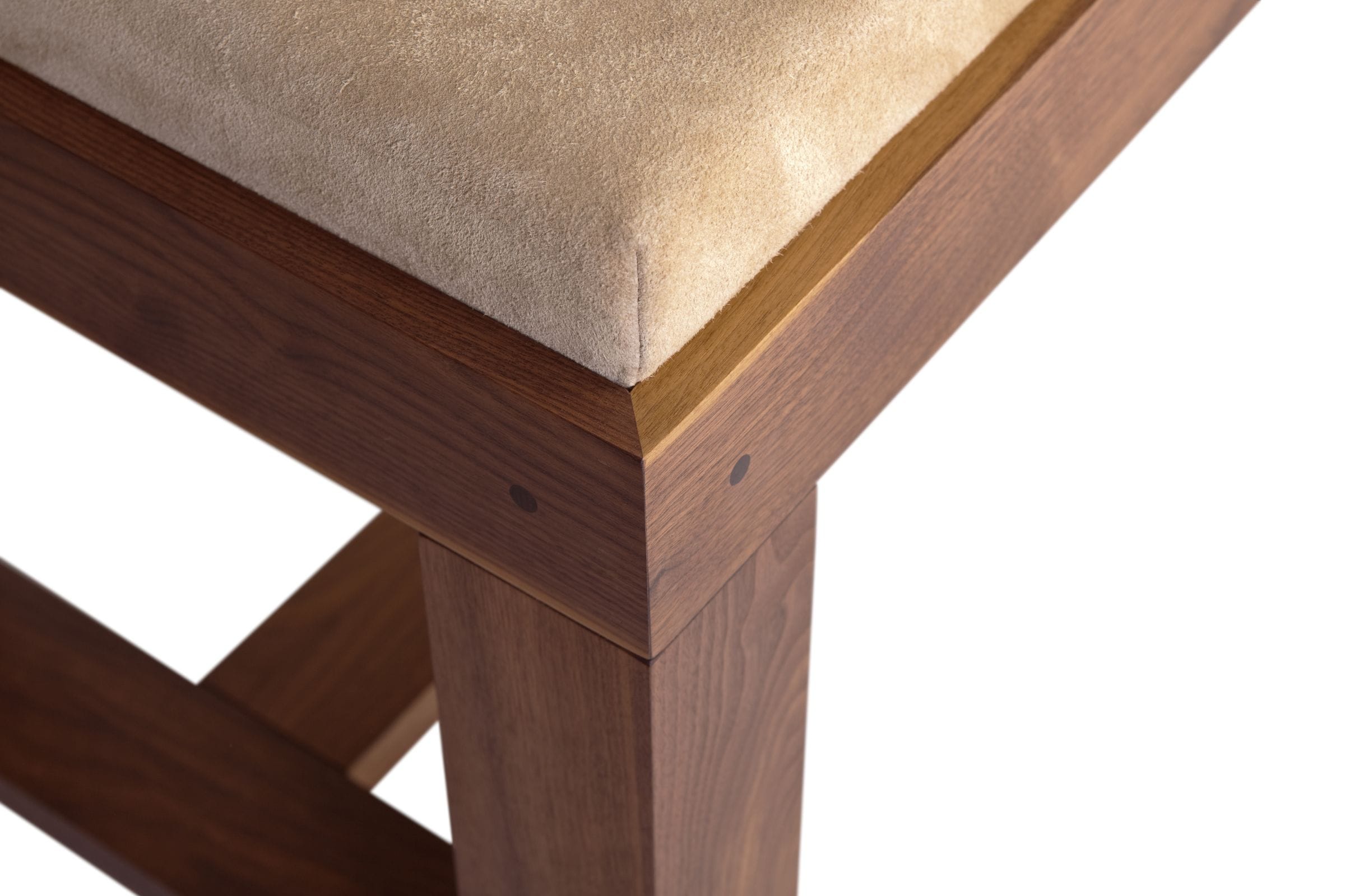 Close-up of a walnut bench corner joint with pegged leg and suede cushion