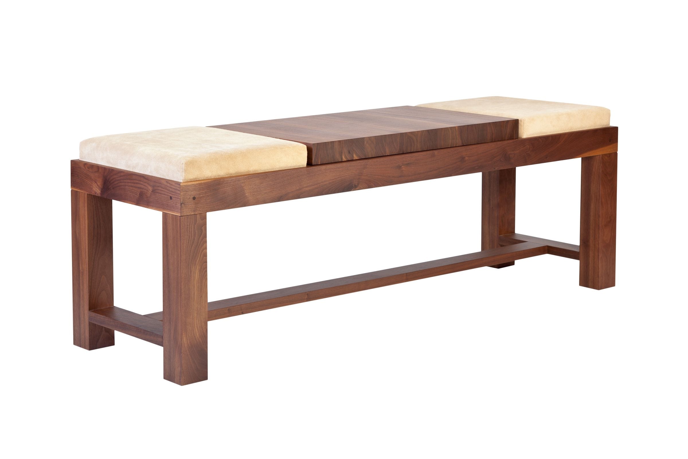Angled view of a walnut bench with cream suede cushions and chunky square legs