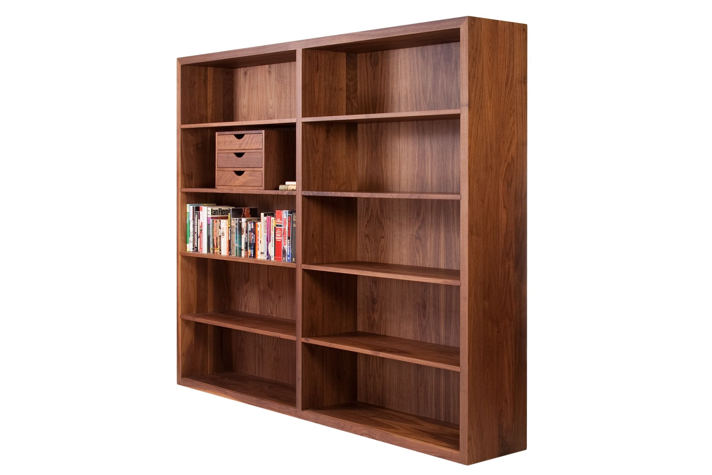 Bespoke walnut bookcase with paperbacks and a small drawer unit on its shelves