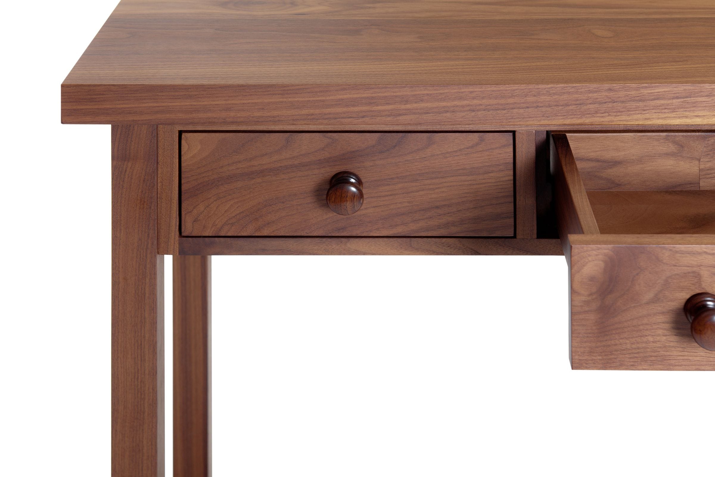 Detail of a walnut console table corner showing drawer front and tapered leg