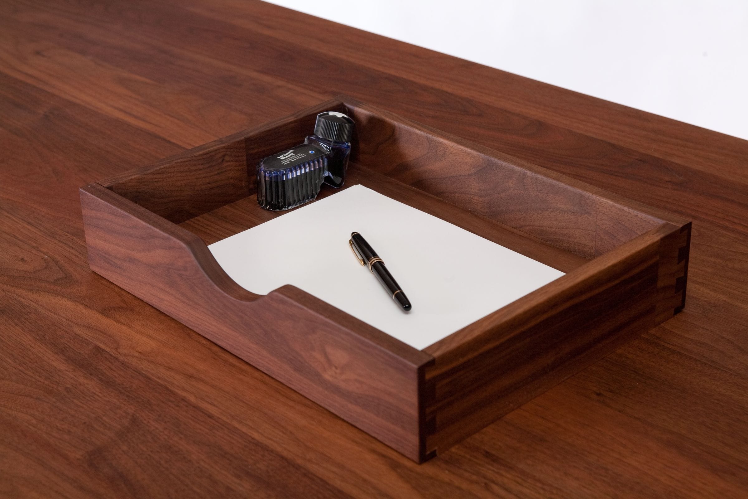 Walnut desk tray holding paper, a fountain pen and a bottle of ink