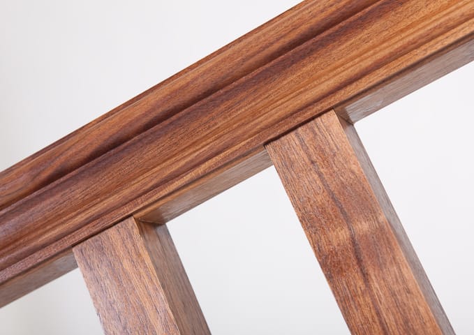 Detail of moulded walnut top rail meeting square spindles on a bench back