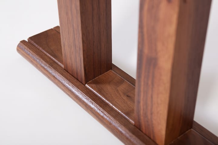 Close-up of square walnut uprights joined to a moulded base rail