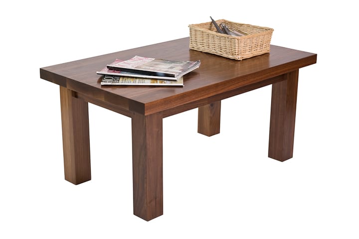 Chunky-legged walnut coffee table with magazines and a wicker basket on top
