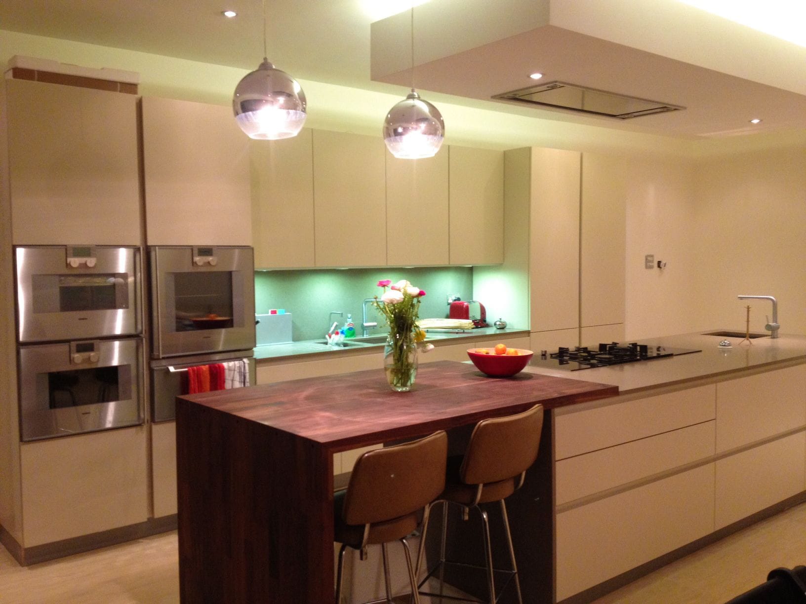 Walnut wide block breakfast bar with tan bar stools in a cream kitchen with pendant lights