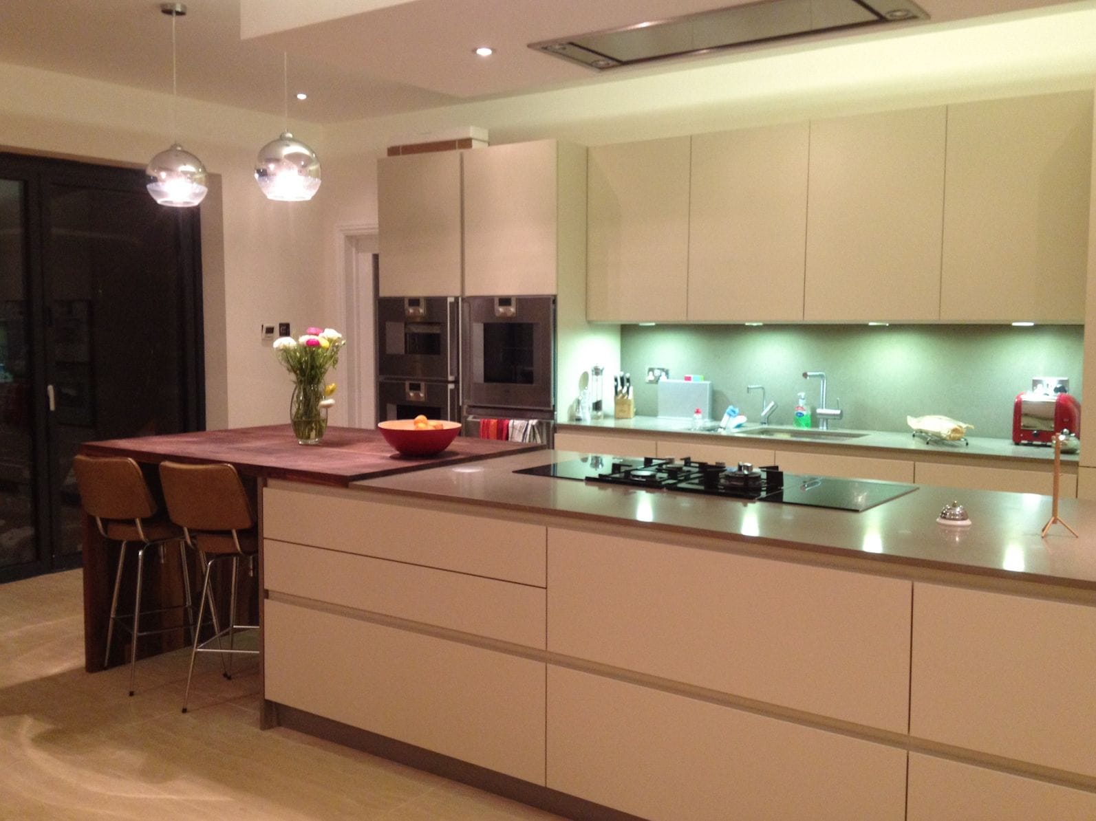 Walnut breakfast bar extending from a cream island with gas hob and bar stools